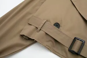 Close-up detail of women's casual khaki trench coat featuring raw edge hem and stylish belt buckle.