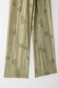 Vue rapprochée de pantalons plissés transparents et légers avec imprimé botanique et textures.