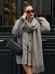 Detailed view of stylish grey knit coat and matching scarf with chic buttons and cuffs.