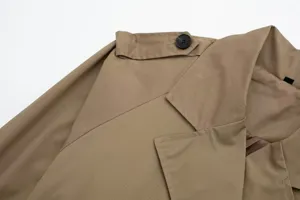 Close-up detail view of the khaki trench coat featuring lapel collar, epaulette and black button.
