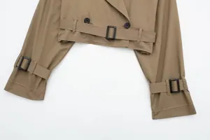 Detailed shot of women cropped khaki trench coat featuring raw edges, belt and buttons.