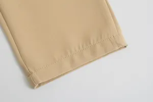 Close-up detail of khaki trouser hem, showing fine fabric texture and neat stitching.