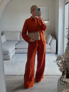 Vista dettagliata della camicia ampia a maniche lunghe e dei pantaloni larghi color ruggine.