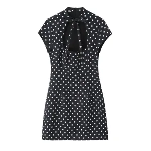 Detailaufnahme des schwarz-weißen Polka-Dot-Minikleids mit Bindkragen und Ausschnitt.