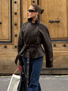 Close-up detail of stylish brown leather jacket with belt, vintage European street style.