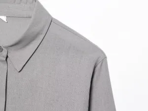 Vista di dettaglio della camicia grigia a maniche lunghe, stile colletto minimalista.