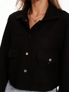 Detalle chaqueta camisa tweed negro, cuello solapa, bolsillos, botones metal.