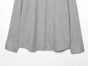 Primo piano dei dettagli della camicia grigia a maniche lunghe e della trama del tessuto.