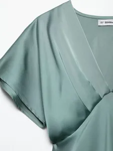 Close-up of elegant V-neck satin dress detail, showing smooth texture and exquisite pleated design.
