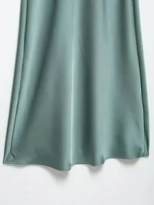 Silk satin dress detail showcasing smooth texture, elegant drape, and beautiful sage green color.