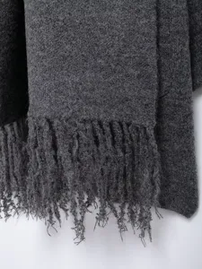 Detailed close-up of dark gray knit fabric featuring stylish fringe, ideal for seasonal wear.
