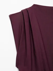 Close-up detail of stylish asymmetrical draped shoulder top fabric in dark burgundy hue.