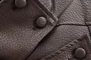 Gros plan détaillé d'une veste en cuir marron grain litchi avec boutons et coutures.
