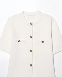Gros plan détaillé de l'élégant cardigan en tricot blanc à manches courtes et boutons dorés.
