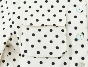 Close-up of a stylish polka dot shirt detail featuring a chest pocket and buttons.