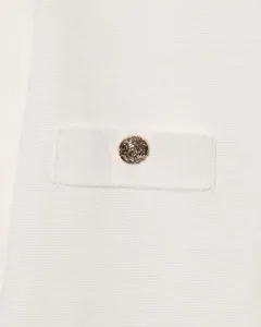 Gros plan de la poche d'un cardigan blanc en tricot avec bouton doré texturé luxueux.
