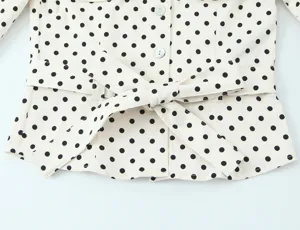 Polka dot blouse detail view, featuring classic black dots on beige fabric with a waist belt.
