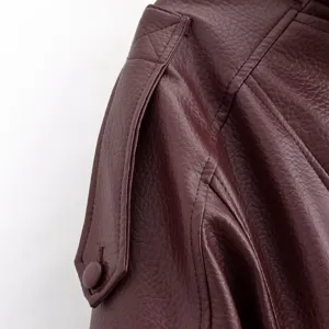 Gros plan sur le détail de l'épaule de veste en cuir synthétique bordeaux avec motif.