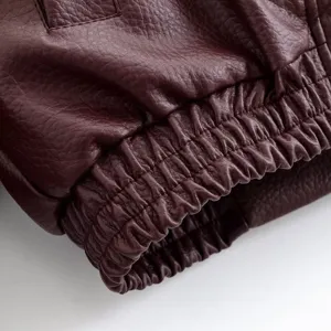 Gros plan détaillé du poignet de veste en similicuir bordeaux avec texture élastique.