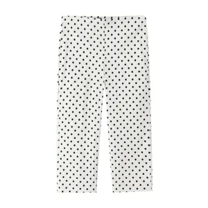 Detailed view of the stylish white trousers featuring a classic black polka dot pattern.