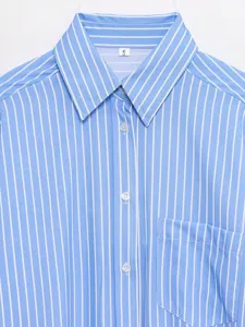 Close-up detail of women's blue and white striped casual button-down shirt with classic collar.