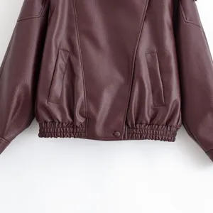Gros plan d'une veste en similicuir bordeaux pour femme avec texture litchi et détails.