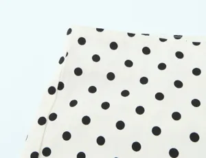 Close up view of classic black and white polka dot fabric detail, featuring fine stitching.