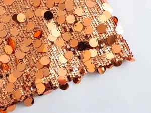 Close-up of sparkling metallic copper sequin fabric detail, mini skirt material texture.