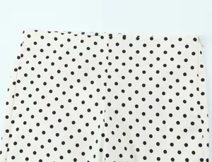 Close up view of women high waist polka dot trousers fabric detail showing side zipper.