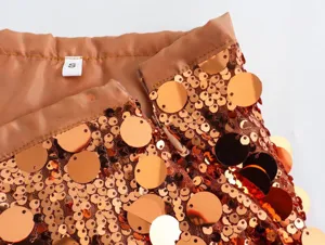 Close-up detail of women copper sequin mini skirt waistband with zipper and S size tag.