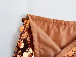 Close up detail of sequin skirt lining and sparkling bronze paillettes fabric texture.