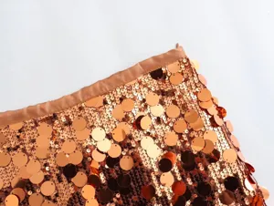 Close-up detail of women's copper sequin skirt fabric, high waist and sparkling texture.