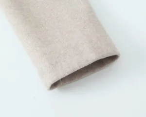 Détail de la manche du manteau en mélange de laine uni, texture fine et coutures nettes.