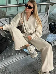 Detailed view of the casual beige zip-up sweatshirt and wide-leg trousers set worn in airport.