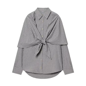 Close-up detail of stylish plaid long sleeve button-up shirt with front tie knot overlay.
