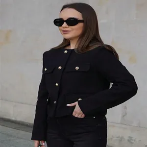 Detail shot of a chic black short tweed jacket featuring elegant gold buttons and stylish front pockets.