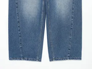 Primo piano dettagliato delle gambe di jeans blu, texture lavata, cuciture a contrasto.