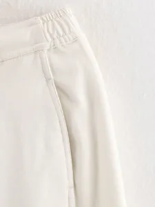 Close-up detail view of white trousers waistband, soft twill fabric texture and pocket.