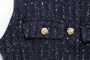 Detail view of dark blue tweed vest, featuring metallic twist buttons and subtle sequins.