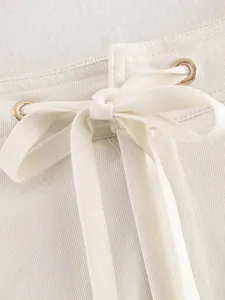 Close-up detail of off-white women pants drawstring waist with metal eyelets and fine twill fabric.