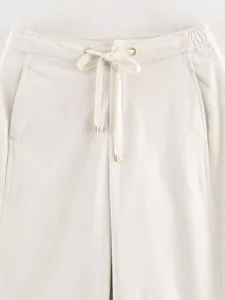 Close-up detail of women's beige wide-leg trousers featuring an elastic drawstring waist.