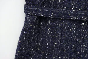 Detailed close-up of dark blue tweed fabric with sequins and metallic threads, belt.