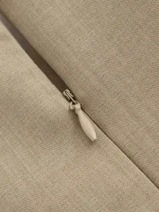 Detail view of beige dress zipper and textured fabric, showcasing fine tailoring and craft.
