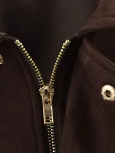 Gros plan sur la fermeture éclair en métal et le bouton-poussoir d'une veste en suédine.