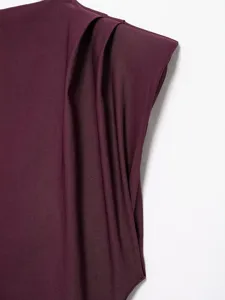 Close-up detail showing the elegant pleated shoulder design and structured shoulder pad of the top.