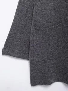 Close-up detail of women's dark gray knit cardigan coat showing sleeve and pocket.