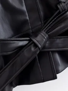 Black faux leather jacket detail, stylish belted short coat close-up for autumn fashion.