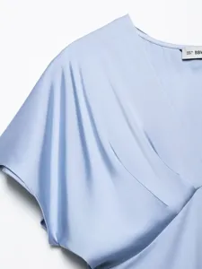 Light blue silk satin dress detail, V-neck short sleeve garment texture close-up view.