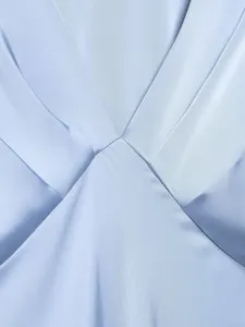 Close-up detail of a light blue satin dress, showing smooth fabric and elegant pleats.