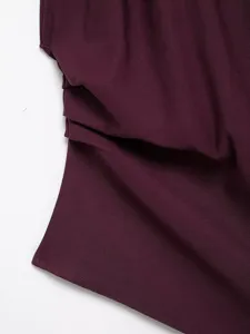 Wine red fabric detail of women asymmetric top featuring pleated texture and elegant drape.